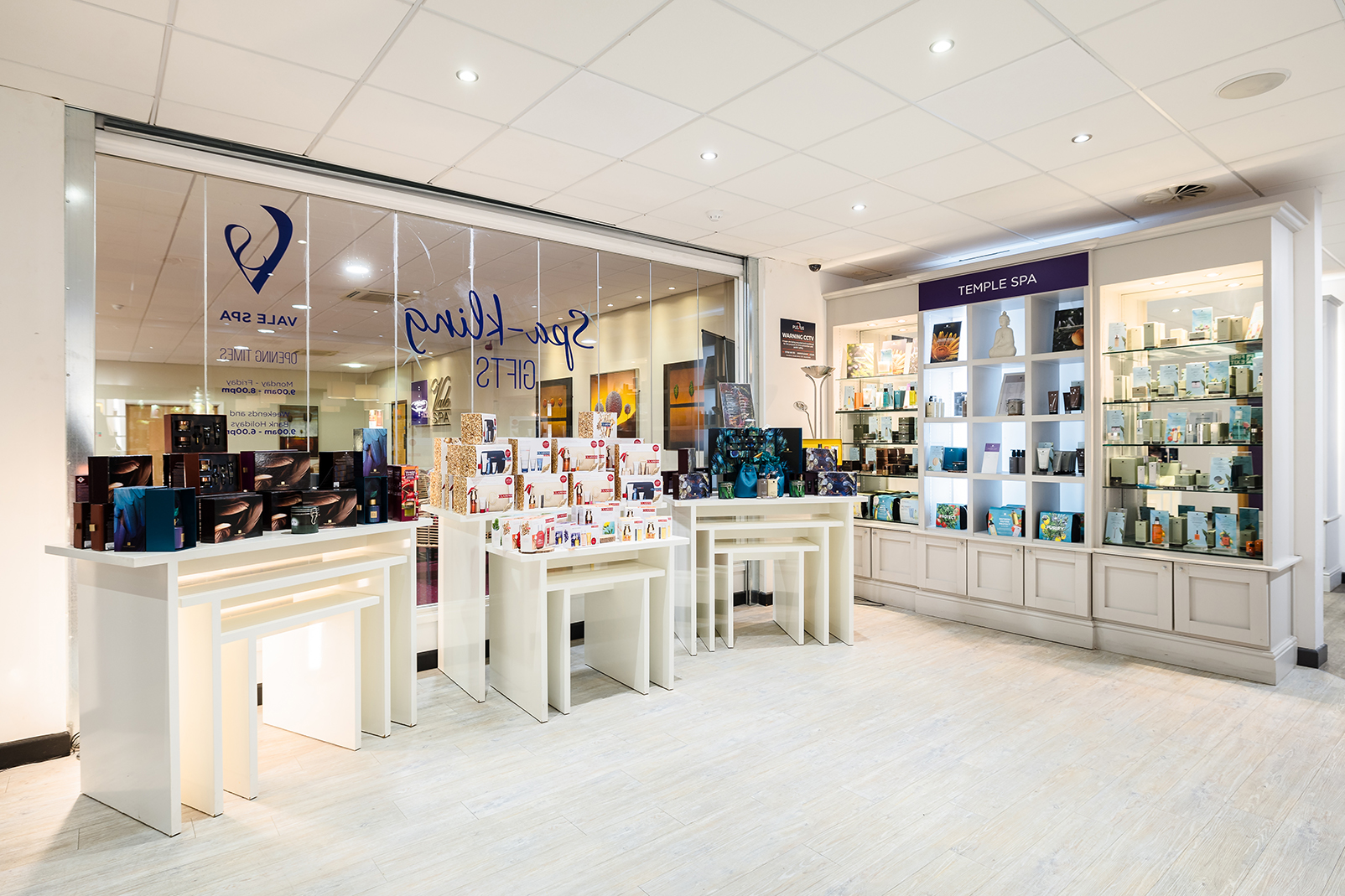 A brightly lit store interior showcasing various skincare and beauty products on white display tables and shelves.