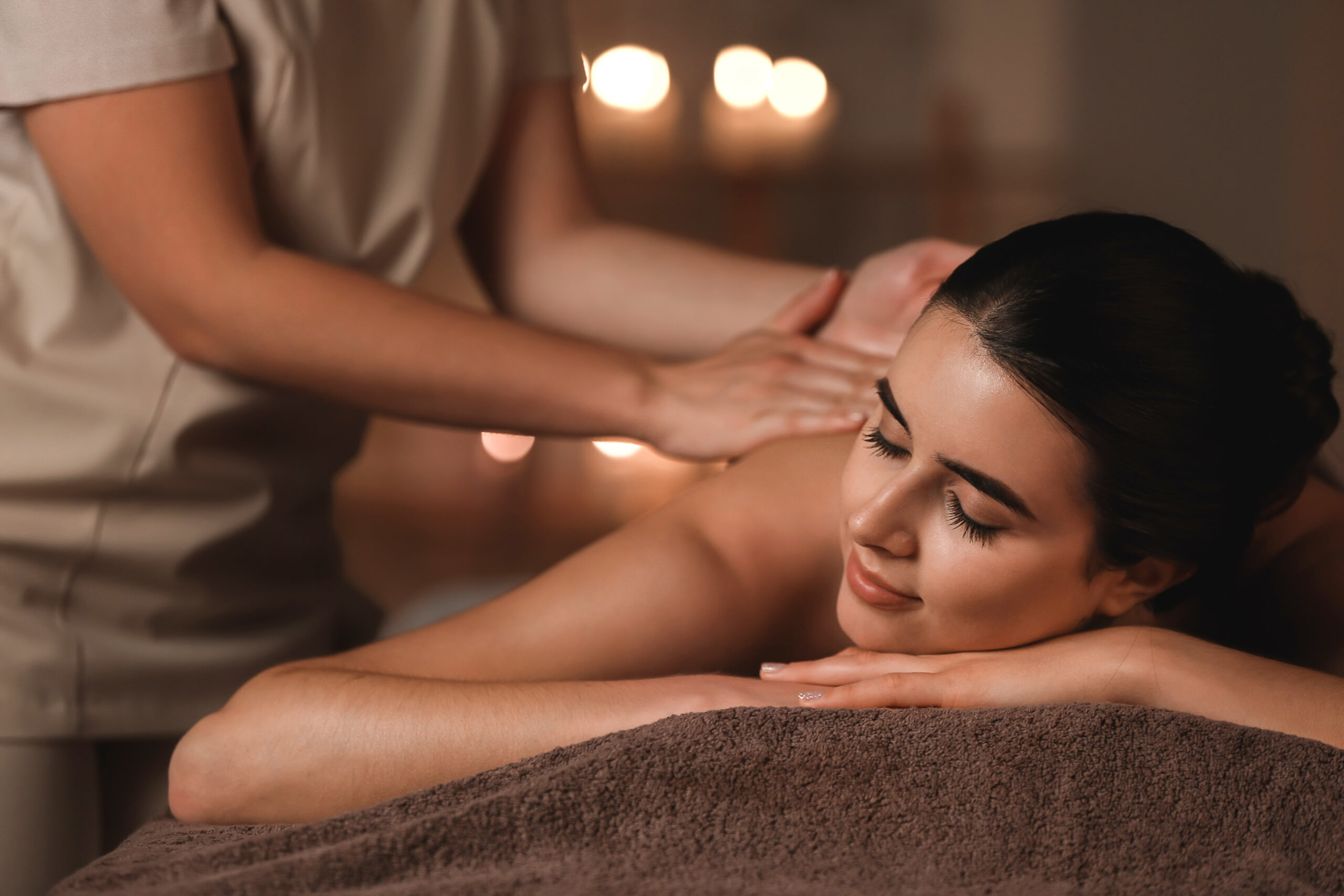 Person receiving a relaxing back massage in a dimly lit spa setting.