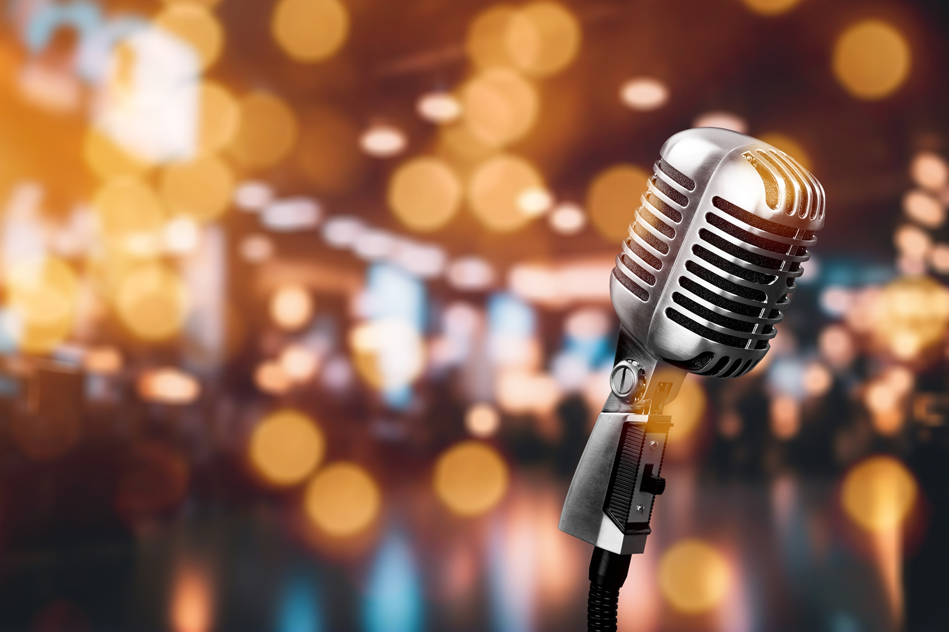 A vintage-style microphone against a blurred background with circular bokeh lights.