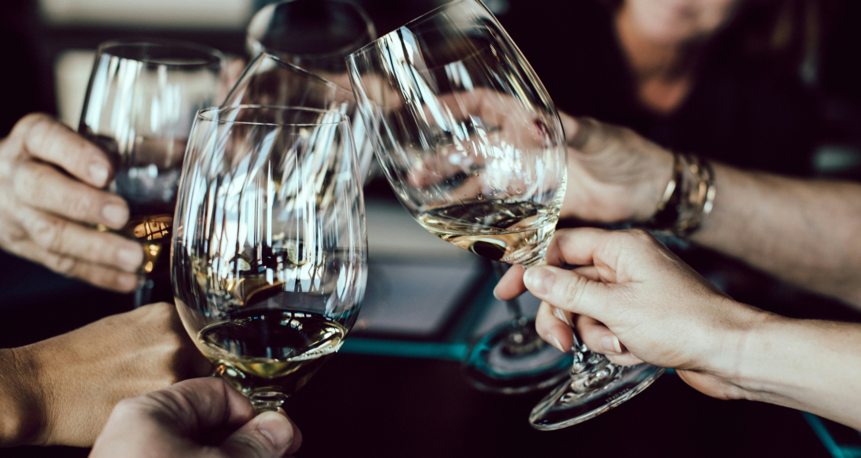 A group of people clinking wine glasses in a toast.