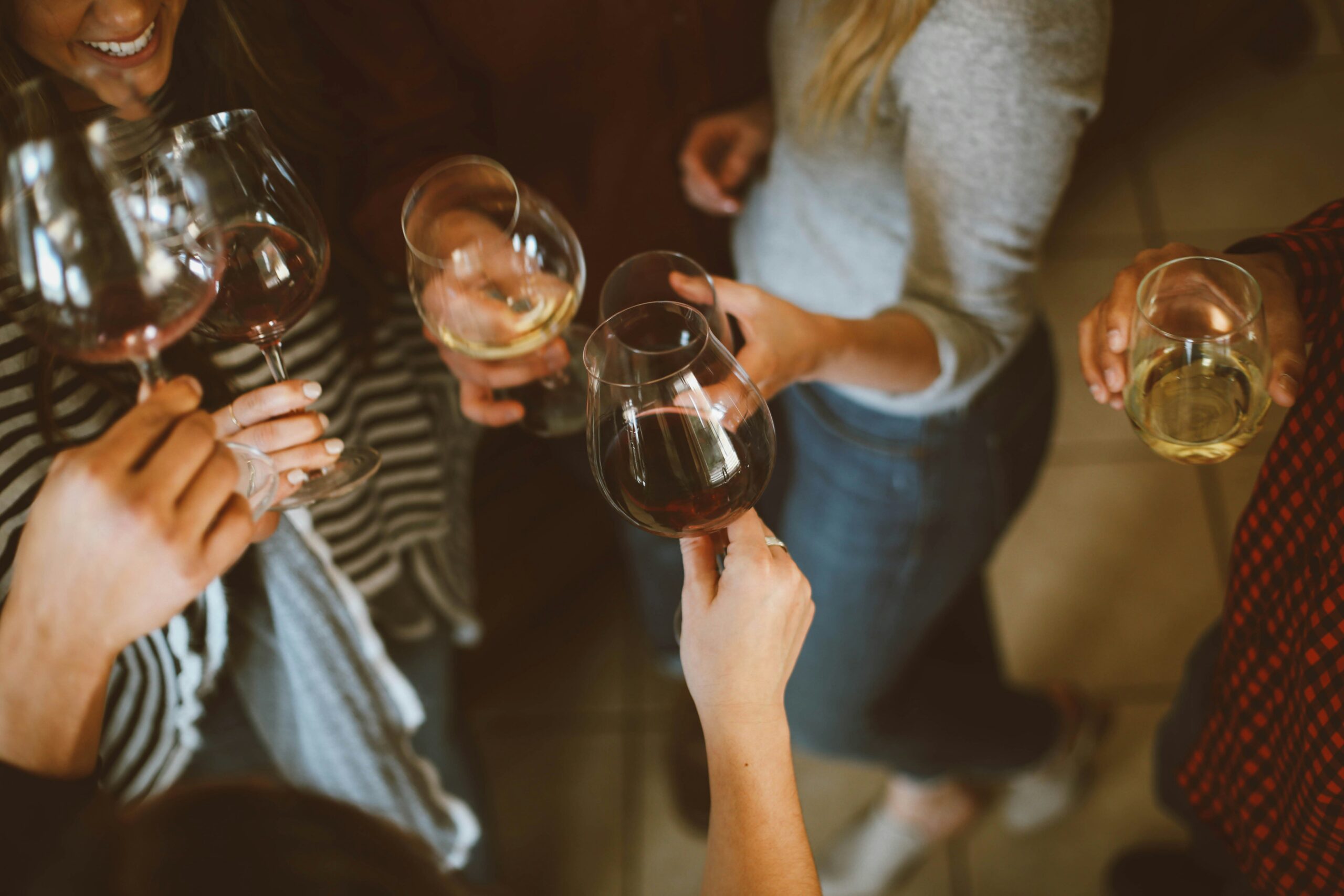 A group of people casually holding and clinking glasses of wine.